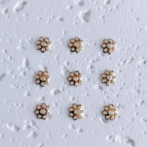 Macro shot of nine 18K gold-plated flower spacer beads for DIY jewelry making