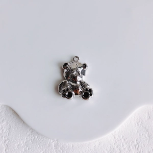 Close-up of polished silver bear charm with black enamel details for DIY jewelry making