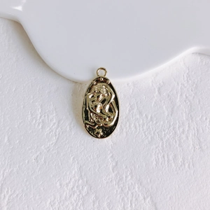 Detailed view of an oval gold-plated pendant with vintage sun relief for DIY jewelry