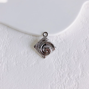 Macro detail of silver square pendant with spiral relief pattern for DIY jewelry making