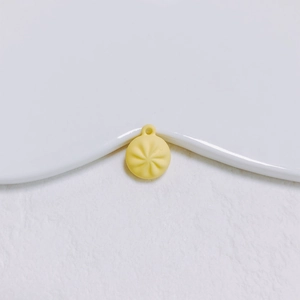 Gros plan d'un pendentif de brioche vapeur jaune clair avec plis réalistes et trou de fixation