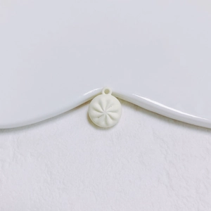Détail macro d'une breloque petit pain crème avec plis réalistes et anneau de suspension
