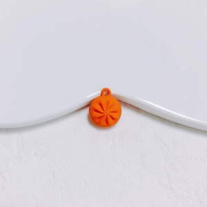 Gros plan d'un pendentif orange en forme de ravioli avec une surface texturée mate