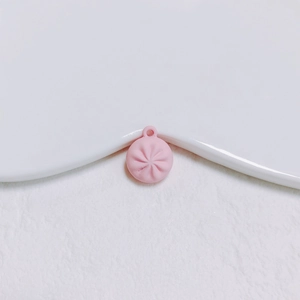Gros plan d'une breloque ronde rose en résine avec texture radiale pour bijoux DIY