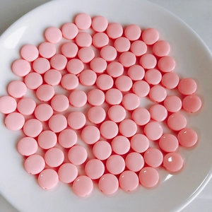 Detalle macro de cuentas de acrílico rosa brillante en plato blanco para joyería DIY