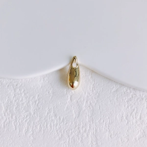 Macro detail of high-polish gold sun pendant with teardrop shape for jewelry making