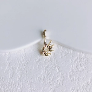 Détail d'un pendentif feuille de bambou dorée avec finition polie et texture métallique