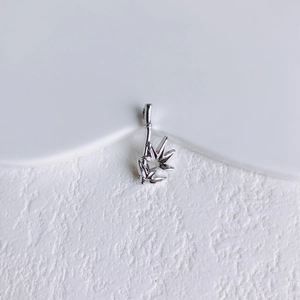 Détail macro d'un pendentif bambou en argent avec gravure de feuilles sur fond de pierre