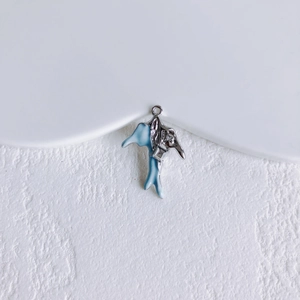 Macro detail van een zilveren dolfijn hanger met lichtblauw emaille en klein kristalletje