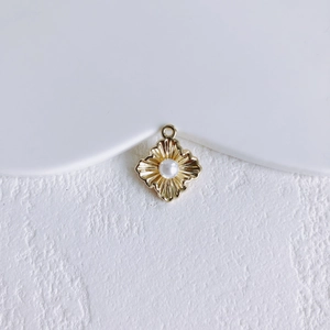 Detailopname van vintage gouden bloemhanger met parel op minimalistische witte steen