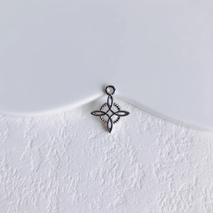 Gros plan d'un pendentif étoile argenté avec texture perlée sur un socle en pierre blanche