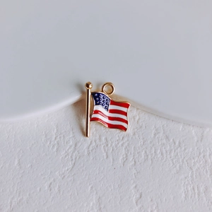 Macro shot of waving US flag charm with golden plating and red white blue enamel details