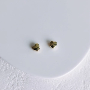 Vue détaillée de pendentifs en cœur dorés polis sur un support d'exposition blanc