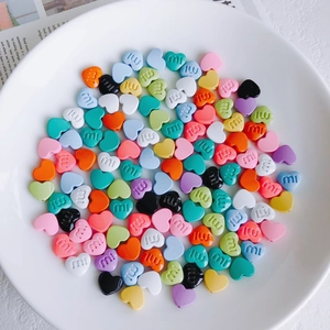 Makroaufnahme bunter herzförmiger DIY-Perlen mit Mi-Buchstabendruck in einer Schale