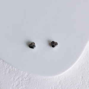 Gros plan de boucles d'oreilles cœur argentées avec une surface polie miroir