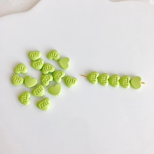 Detail von hellgrünen Macaron-Herzperlen mit mi-Gravur für DIY-Schmuckherstellung
