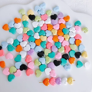 Detail von bunten Macaron-Herzperlen mit Buchstabengravur für DIY-Haarclip-Bastelarbeiten