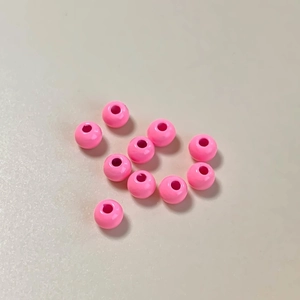Detalle macro de once cuentas redondas lacadas en rosa vibrante para joyería DIY y manualidades