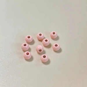 Primer plano de diez cuentas rosas brillantes de esmalte con agujeros para joyería DIY