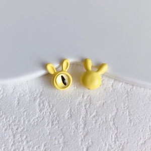 Macro detail of cute yellow rabbit bead for DIY jewelry making on white textured surface
