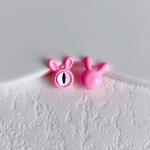 Close-up of pink rabbit evil eye beads for DIY jewelry making on white display