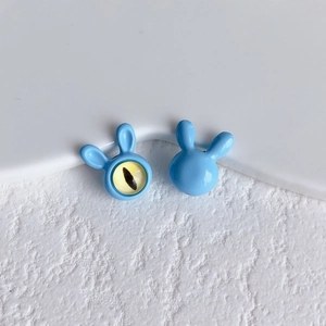 Macro shot of blue bunny alloy beads with cat-eye stone detail on a textured white background