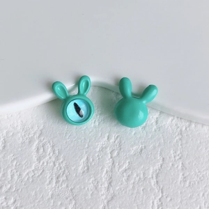 Macro detail of cute green rabbit alloy beads with blue cat-eye effect and smooth lacquer