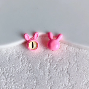 Detail of pink resin bunny beads showing front with yellow eye and smooth glossy back view