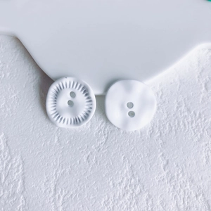Detailed view of white textured floral buttons on a minimalist stone background