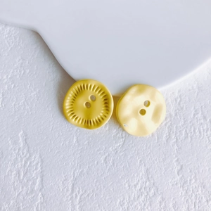 Detail of yellow flower-shaped metal buttons with dual holes for DIY jewelry making