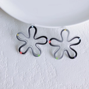 Macro shot of transparent acrylic floral pendants with colorful dots and artistic black lines