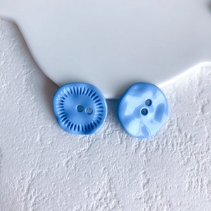 Detail of two sky blue decorative buttons with radial texture and wavy smooth surface