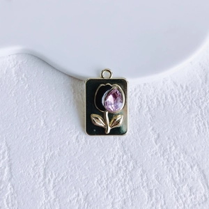 Macro shot of rectangular metal tulip pendant with black enamel and purple crystal drop
