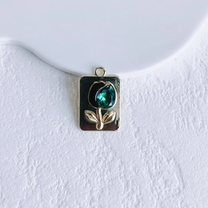 Detail of vintage tulip pendant with green gemstone and black enamel in gold frame
