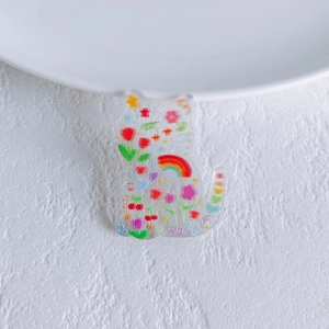 Detail of a cat-shaped acrylic pendant with colorful hand-drawn floral and rainbow patterns