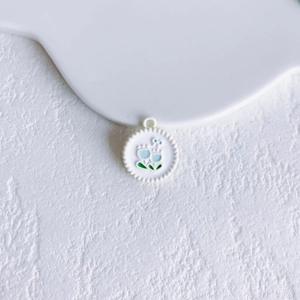 Close-up of a floral alloy pendant with blue enamel flower and scalloped metal edge