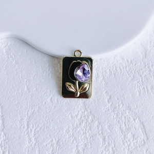 Detailed view of a gold tulip pendant with a purple crystal gemstone and black floral petal
