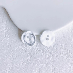 Macro detail of white irregular dual-hole buttons with elegant matte texture and relief