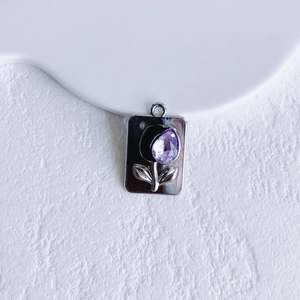 Detailed macro view of silver rectangle pendant with tulip design and purple gemstone