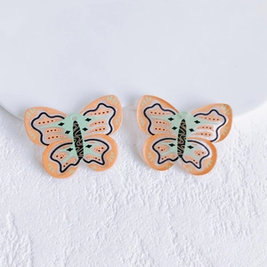 Detail of acrylic butterfly charms with orange and green patterns for DIY jewelry making