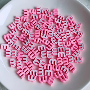 Detailed view of pink and white M-shaped beads with side holes for DIY jewelry making