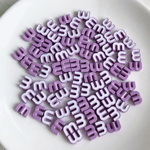 Macro detail of purple candy-colored letter M beads for DIY jewelry and hair accessories