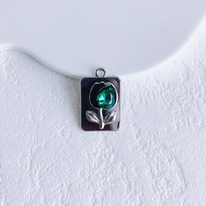 Close-up of a silver tulip heart pendant with a faceted green teardrop gemstone