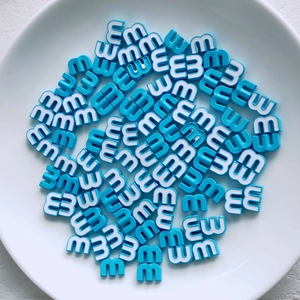 Macro shot of sky blue letter m beads in a ceramic tray for DIY jewelry making