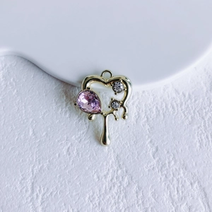 Close-up of golden heart pendant with pink pear-shaped crystal and small diamonds