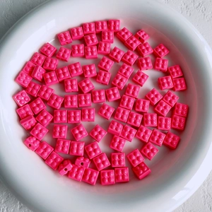 Macro view of bright pink macaron square resin beads for DIY jewelry making
