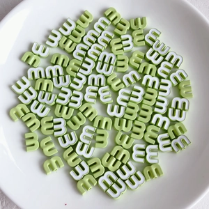 Macro shot of candy-colored light green M letter alloy beads for DIY jewelry making
