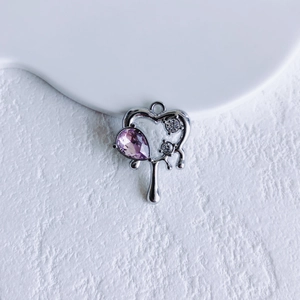 Macro detail of a silver fluid heart pendant with purple gemstone and zirconia
