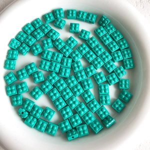 Macro detail of mint green 2x2 brick-style beads for DIY jewelry making in a white bowl