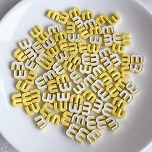 Close-up of yellow and white candy-colored letter M alloy beads for DIY jewelry making